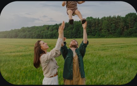 A parent lifting a child in a field at dusk.