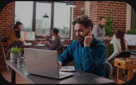 A man working on a laptop in a busy co-working space.