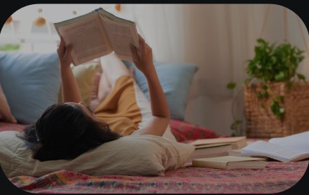 A child reading a book on a bed.