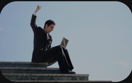 A man sitting on steps with a laptop, arm raised.